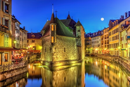 Vue nocturne du Palais de l'Isle, à Annecy, se reflétant dans le canal du Thiou