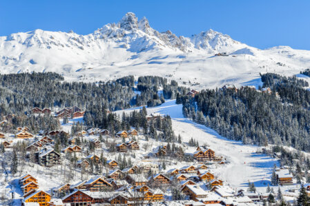 Un village de station dans les Alpes, rempli de chalets authentique, érigé au pied d'un sommet enneigé