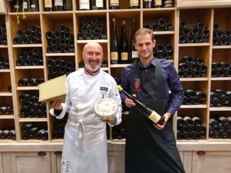 Un sommelier accompagné d'un fromager Meilleur Ouvrier de France devant une cave à vin