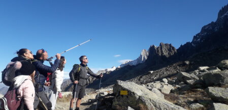 Un guide de moyenne montagne accompagne une famille sur les sentiers des Alpes