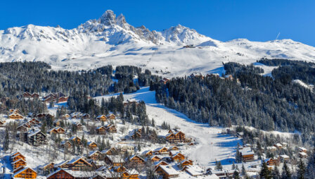 Un village alpin avec de nombreux chalets de bois au pied des montagnes enneigées