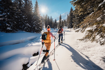 Two people are ski touring in a snow-covered mountain landscape